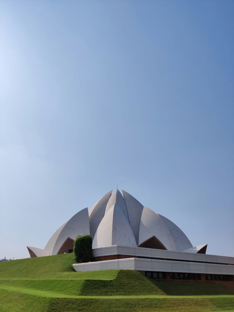 Lotus Temple Delhi exterior side view showing curved marble petals against blue sky