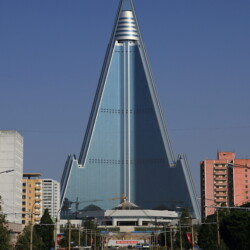Hotel Ryugyong mìl být centrem obchodu a symbolem síly komunistického státu, s výkou 330 metrù aspiroval na nejvyí budovu své doby. Po celé zemi byl prezentován jako technický div severokorejského stavebnictví a objevoval se v novinách nebo na plakátech. Práce na hotelu odstartovaly v roce 1987, slavnostnì mìl být otevøen v èervnu 1989 u pøíleitosti Svìtového festivalu mládee. Jene u na poèátku stavby musela vláda èelit problémùm. Práce se protahovaly, poíraly stále více penìz a èelily zásadním konstrukèním problémùm napøíklad chybìl beton, a kdy ho dìlníci mìli zrovna k dispozici, dosahoval takové kvality, e hrozilo zøícení celé stavby. Èasto také vùbec nefungovala elektøina. Náklady stoupaly, pøed ukonèením stavby v roce 1992 se vyplhaly na celých 750 milionù dolarù, co jsou zhruba dvì procenta severokorejského HDP. Konec pøiel s nedostatkem potravin a elektrické energie a následným hladomorem. Od roku 1992 tak zùstal hotel Ryugyong osamocen, betonová konstrukce bez oken a jakéhokoliv vybavení pøipomínala nenaplnìné sny KLDR. Hotel zkázy, jak se stavbì pøezdívá, je konstruován jako pyramida se tøemi køídly, která stoupají do výky, kde se spojují v kruhový vrchol. V nìm je konstruováno osm otáèejících se podlaí urèených pro luxusní restaurace. Pøesnì 105 pater s rozlohou 360 000 m2 mìlo poskytovat 3000 pokojù, ale skoro dvì desetiletí se kromì holubù v hotelu nikdo ubytovat nemohl. V dubnu 2008 byla obnovena dostavba hotelu. V záøi 2008 vydala Severní Korea oficiální prohláení hotel Ryugyong bude dokonèen v roce 2012, na sté výroèí narozenin Kima Ir-sena. Fakt, e snaha dokonèit hotel není smylená a opravdu se na tom náhrobku nìco dìje, dokládají aktuální fotografie. Hotel dostal sklenìnou fasádu a na vrchol byla instalována telekomunikaèní anténa, nutno ovem podotknout, e investorem byl Egypt.