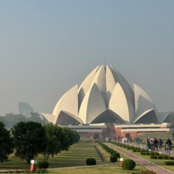 The Lotus Temple sits serenely within landscaped gardens, providing a tranquil escape in bustling New Delhi. Lotus Temple Delhi exterior view with surrounding gardens and landscape setting